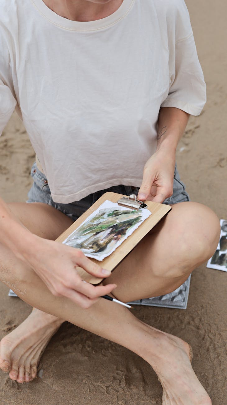 woman sitting on beach drawing