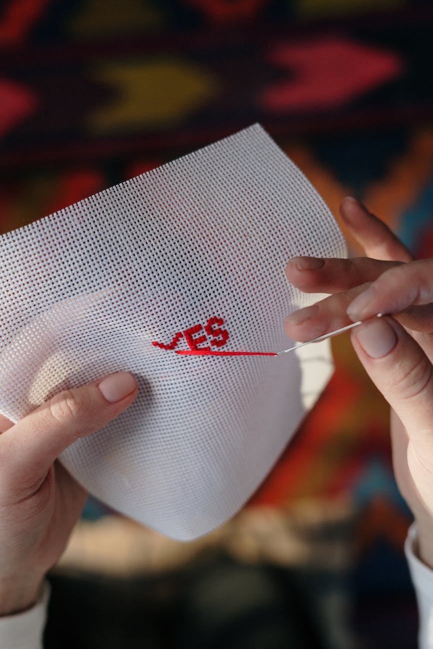 person hand embroidering on white textile