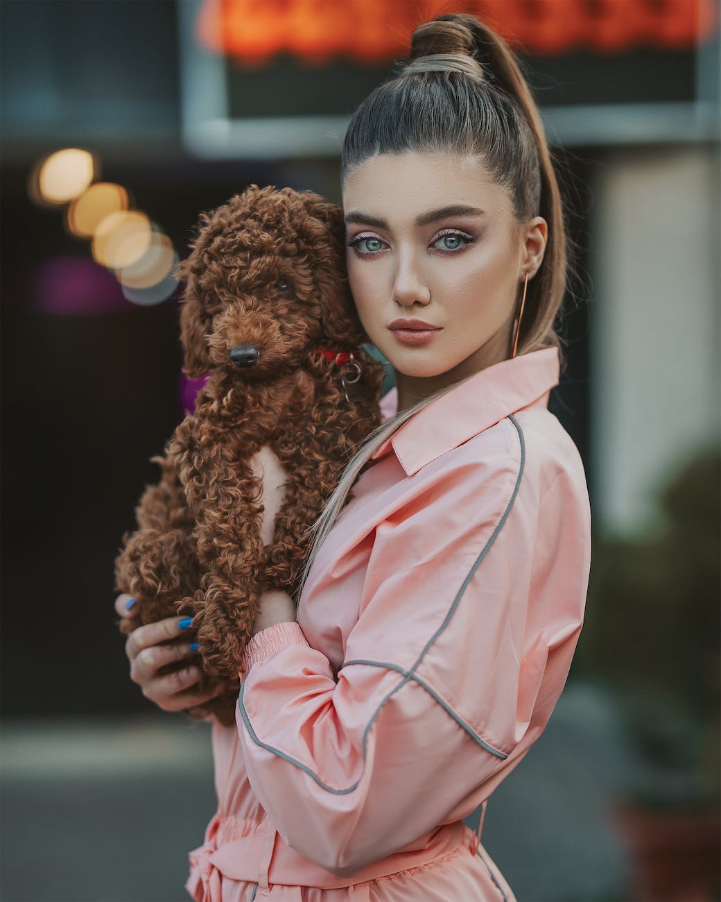 girl in pink long sleeve shirt holding brown dog