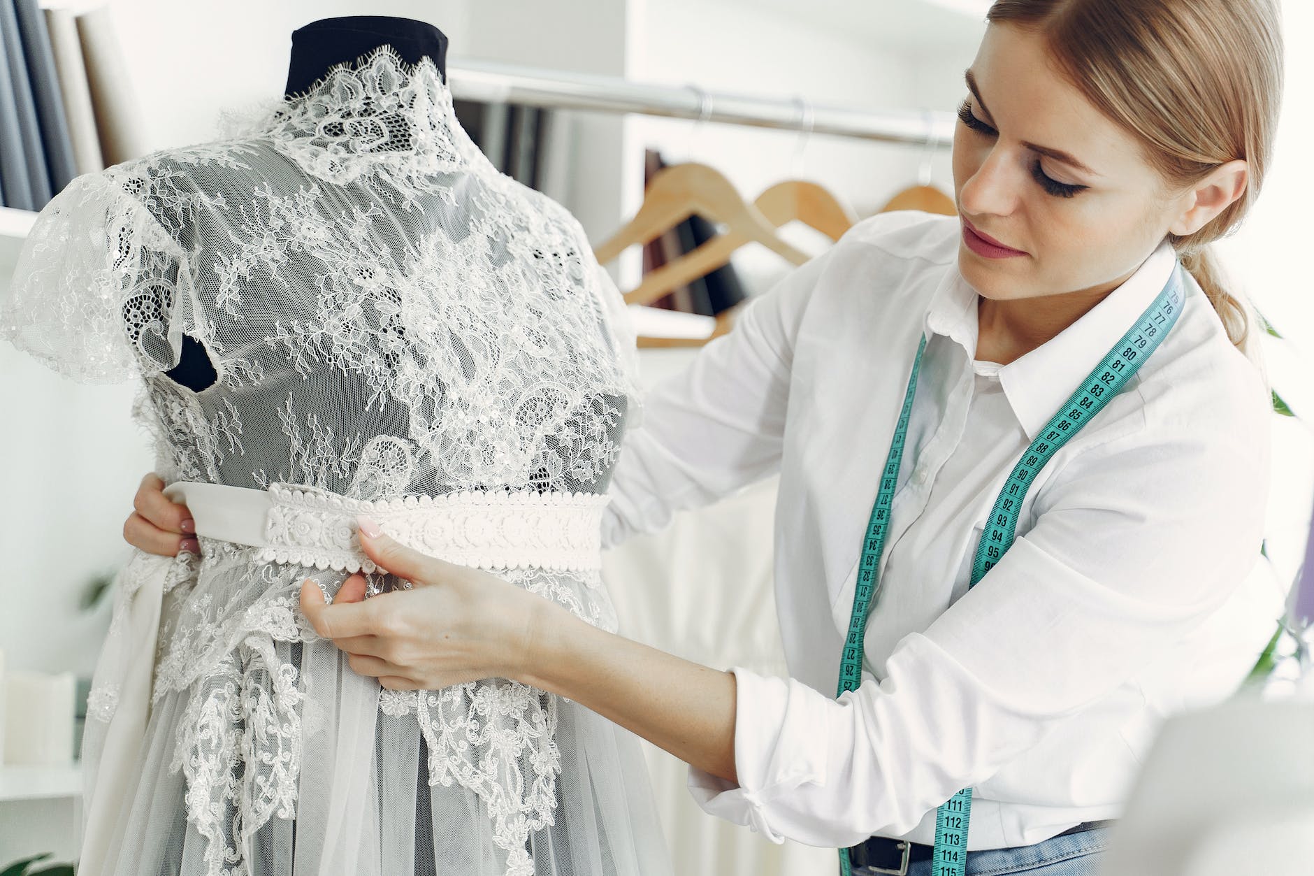 focused female dressmaker creating wedding dress in workshop