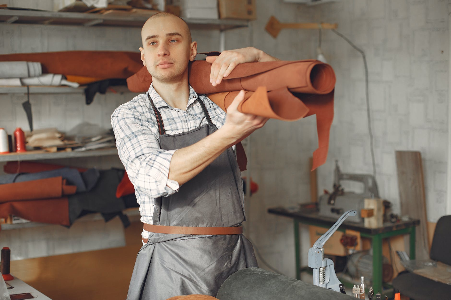 content artisan carrying roll of leather on shoulder