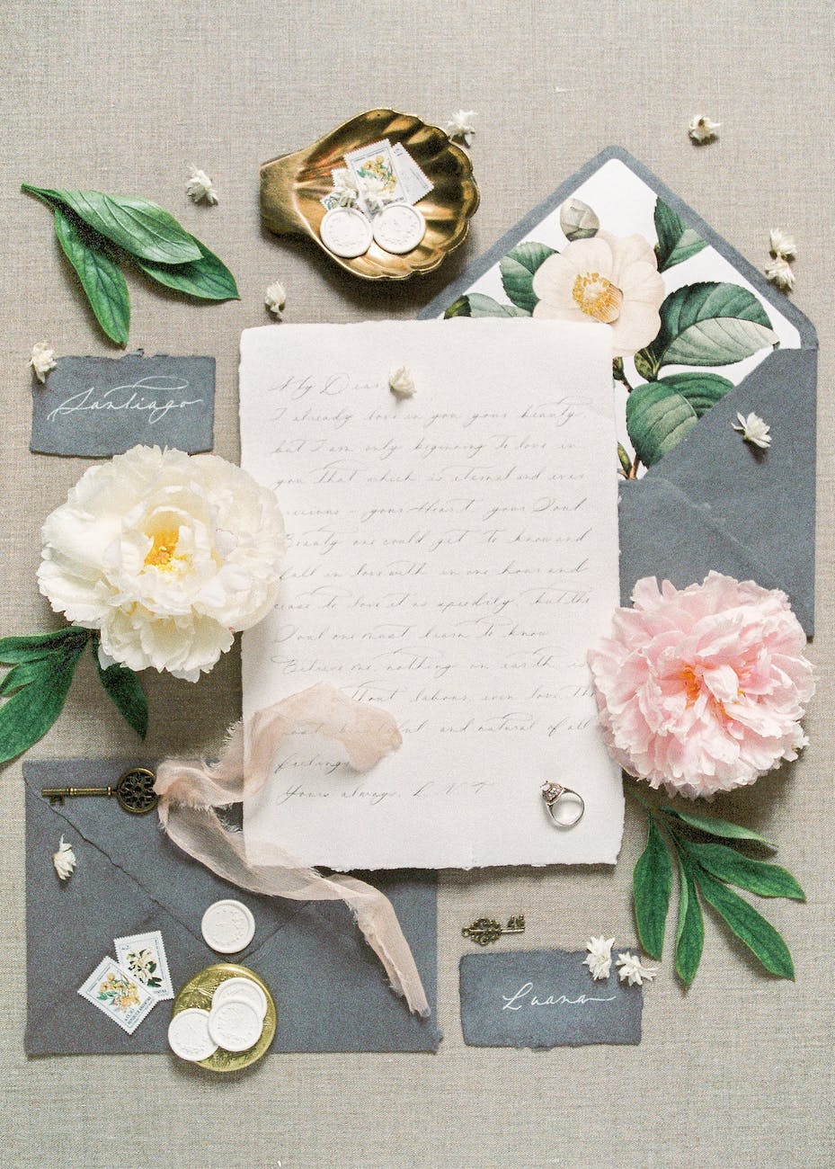 letter with ring beside white and pink flowers