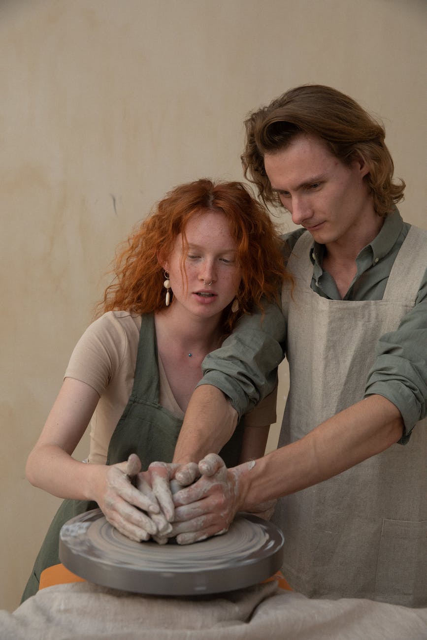 couple creating clay product on potters wheel