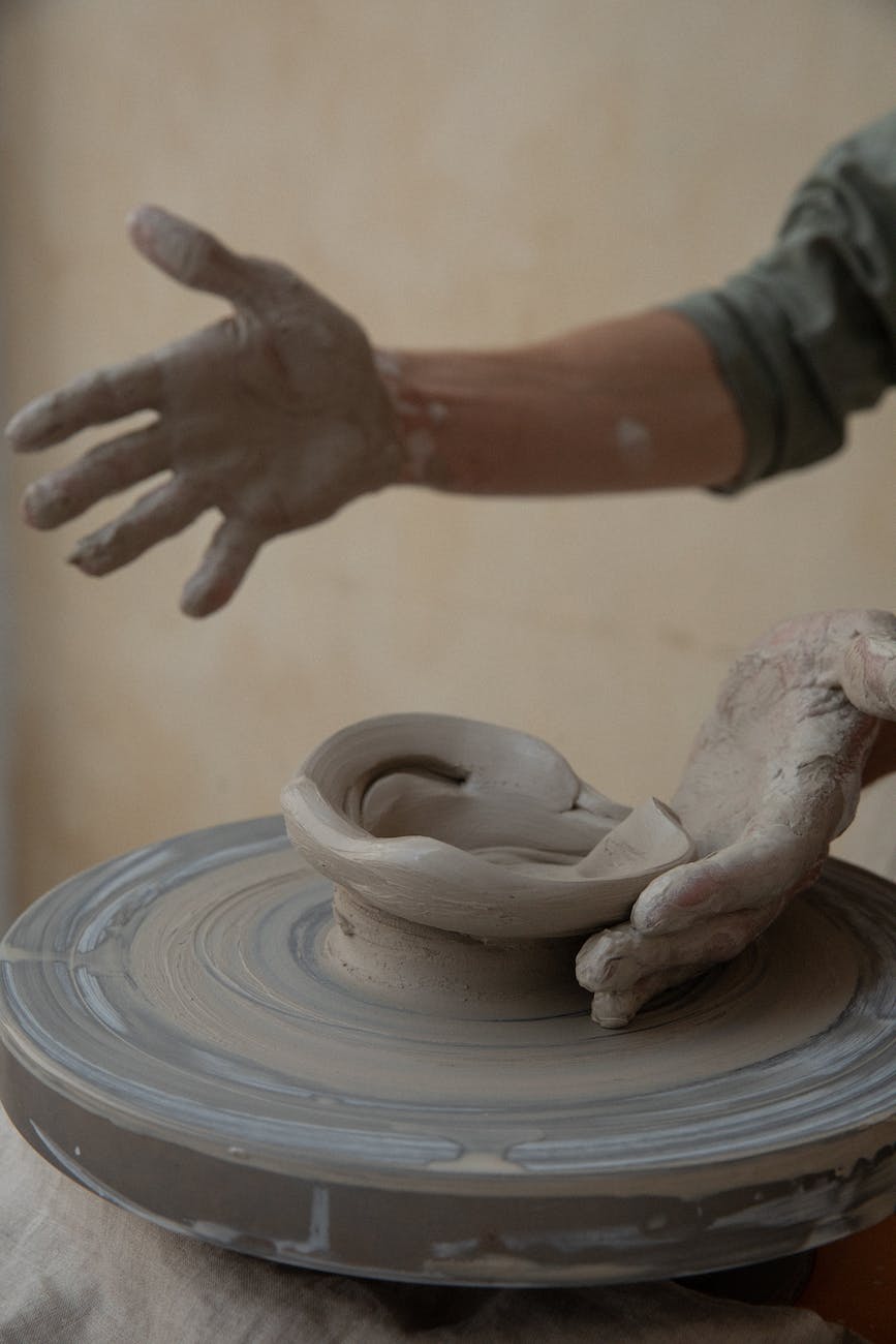 crop man modelling clay bowl on wheel