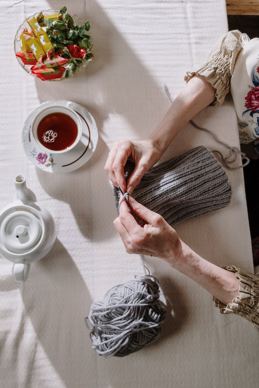 person holding a knitwork beside a cup of tea