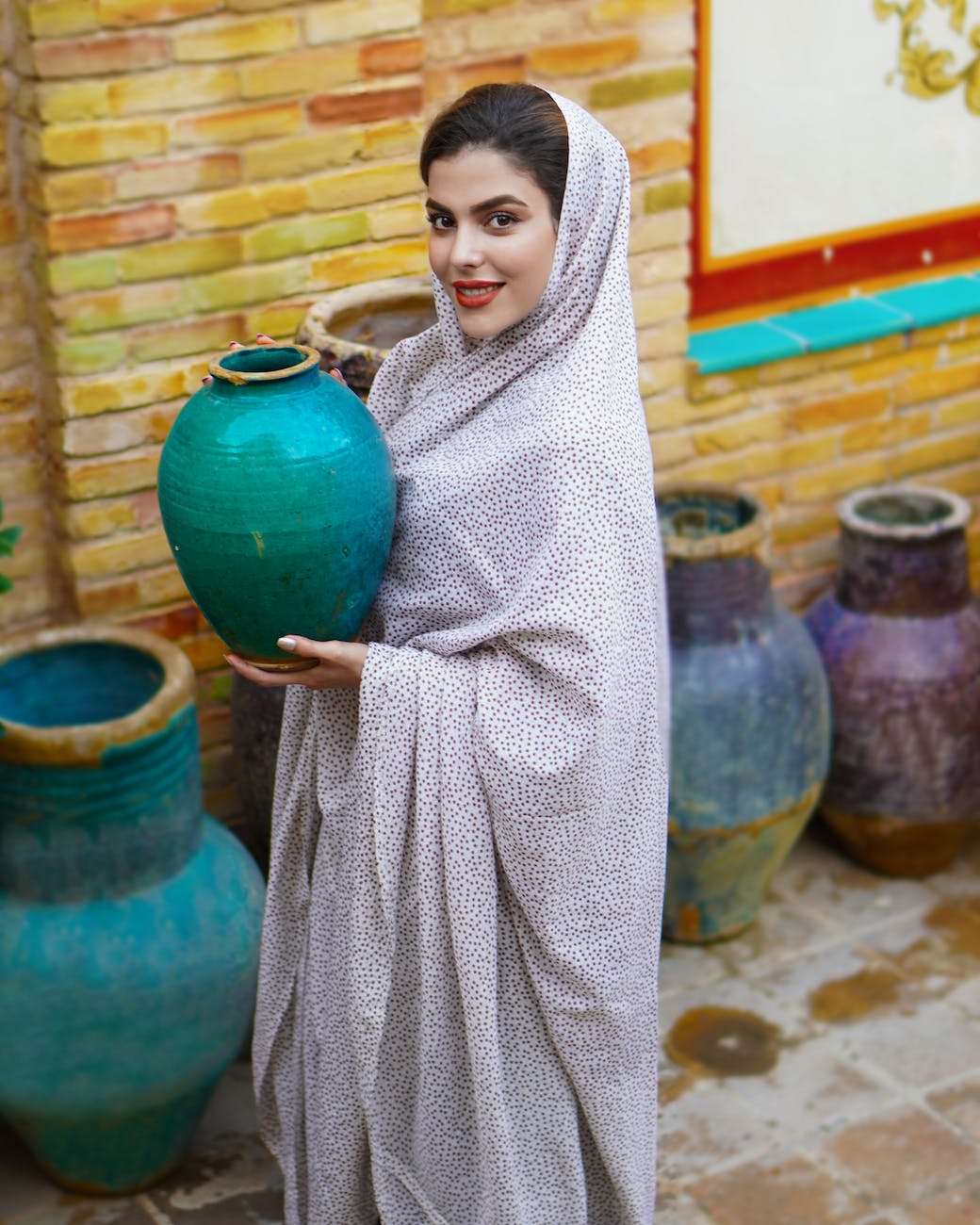 a woman wearing a black and white chador holding a blue pot