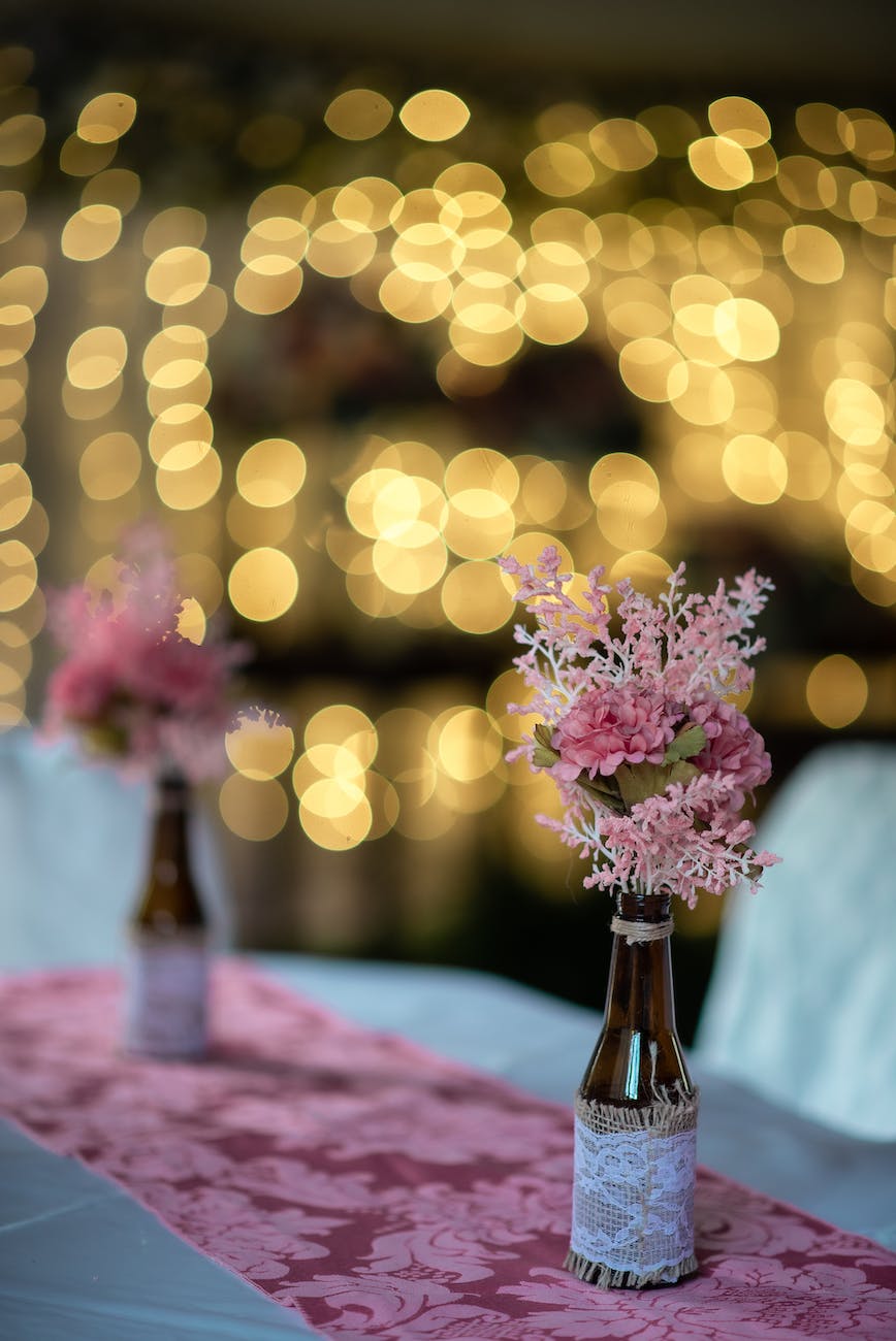 pink flowers in decoupage bottles on banquet table