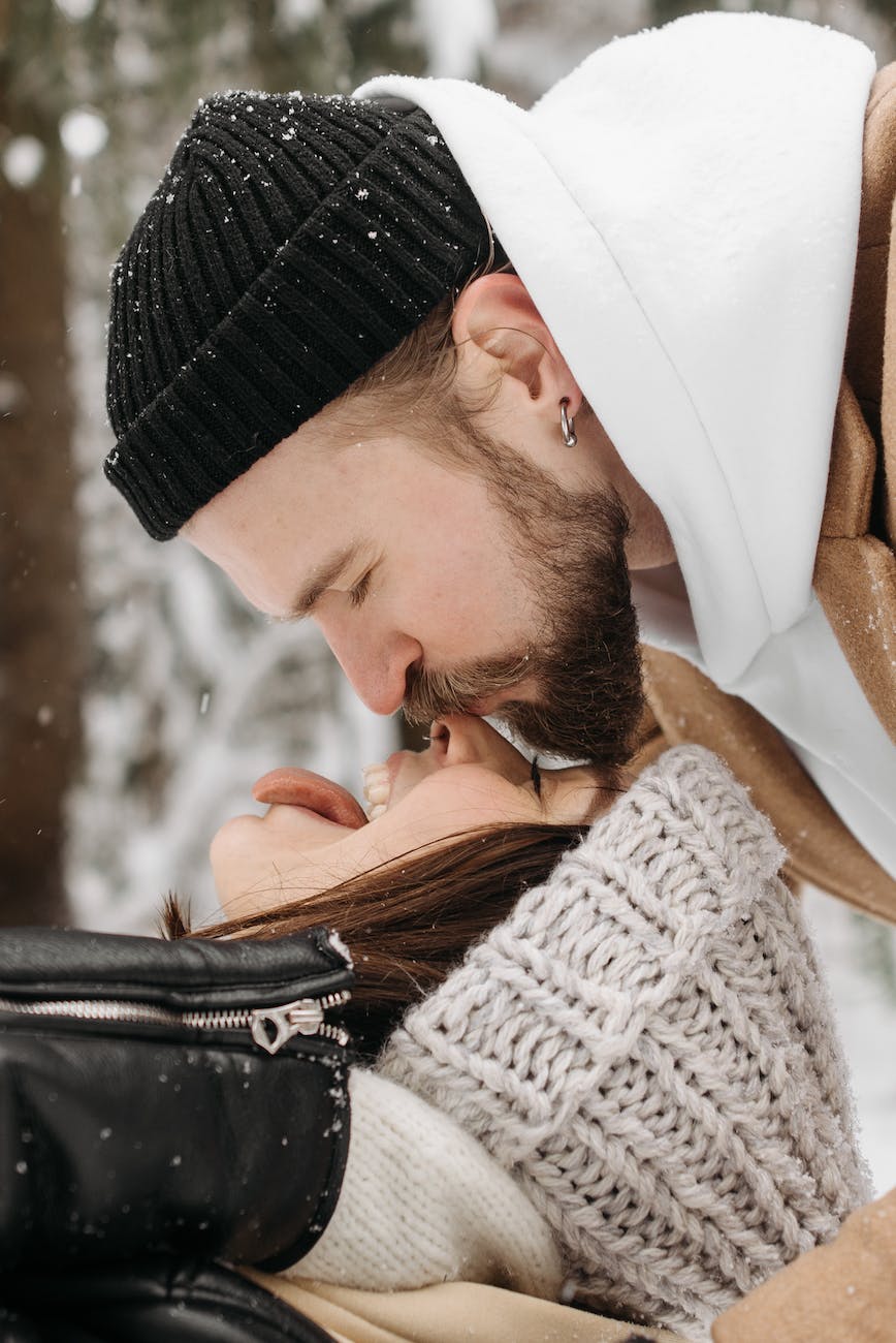 photo of a man with a black knitted cap kissing a woman on the nose