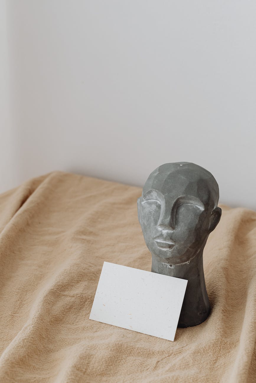 still life with gray head sculpture and blank paper on beige velvet