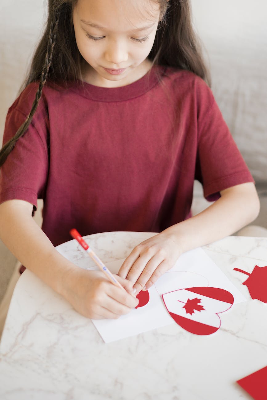 a young girl in red shirt writing on paper