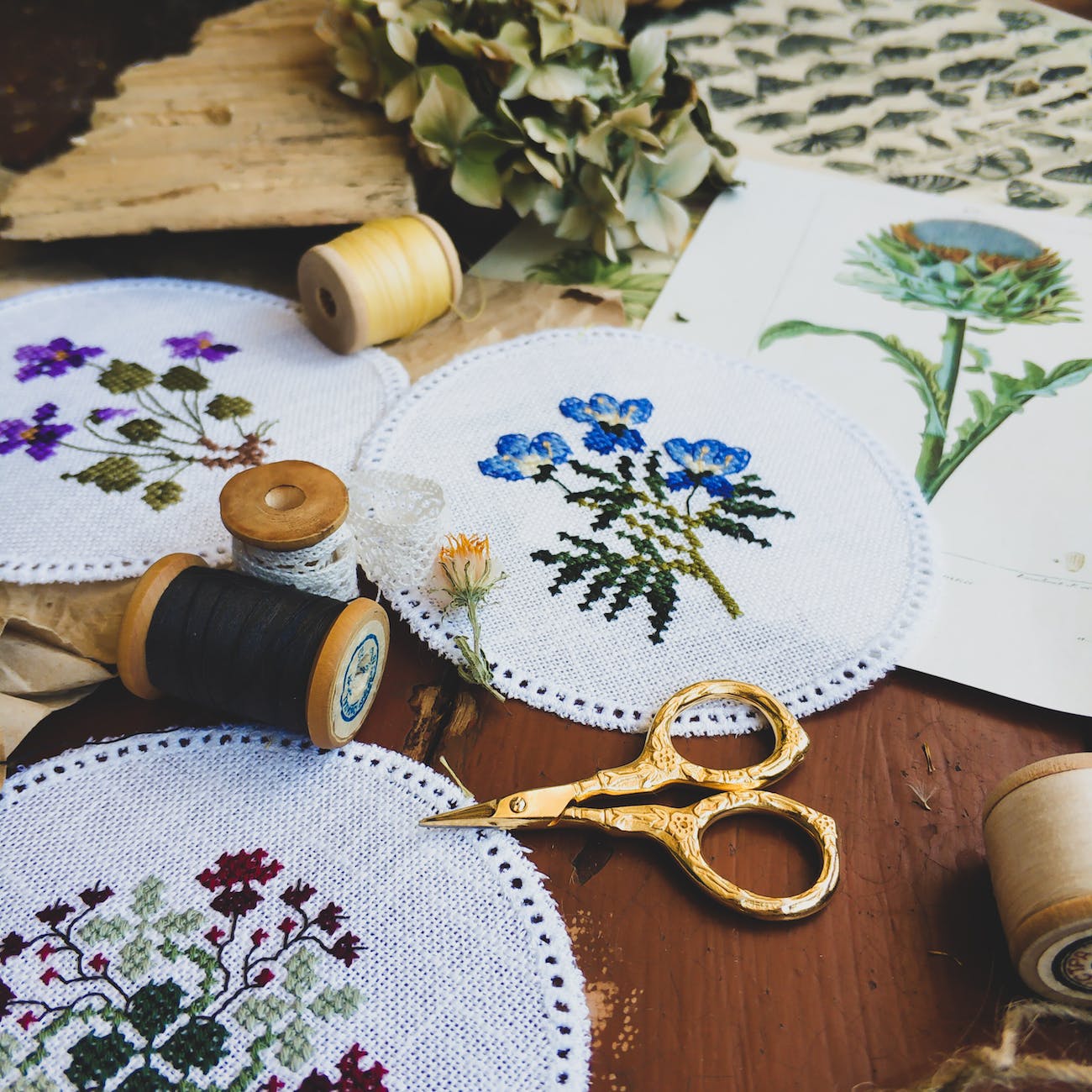 collection of cross stitch embroidery and threads on table