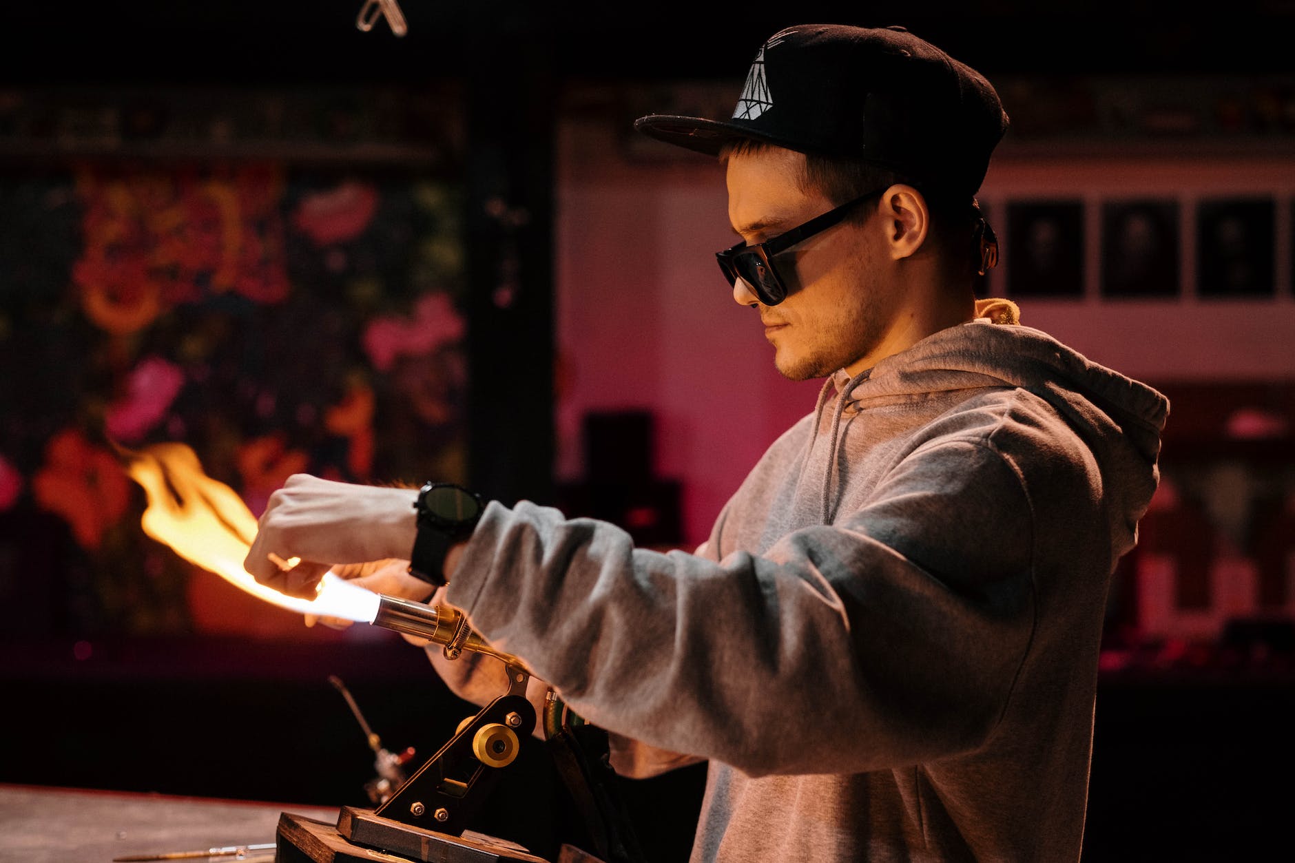 a side view of a man in hoodie jacket working on burning flame