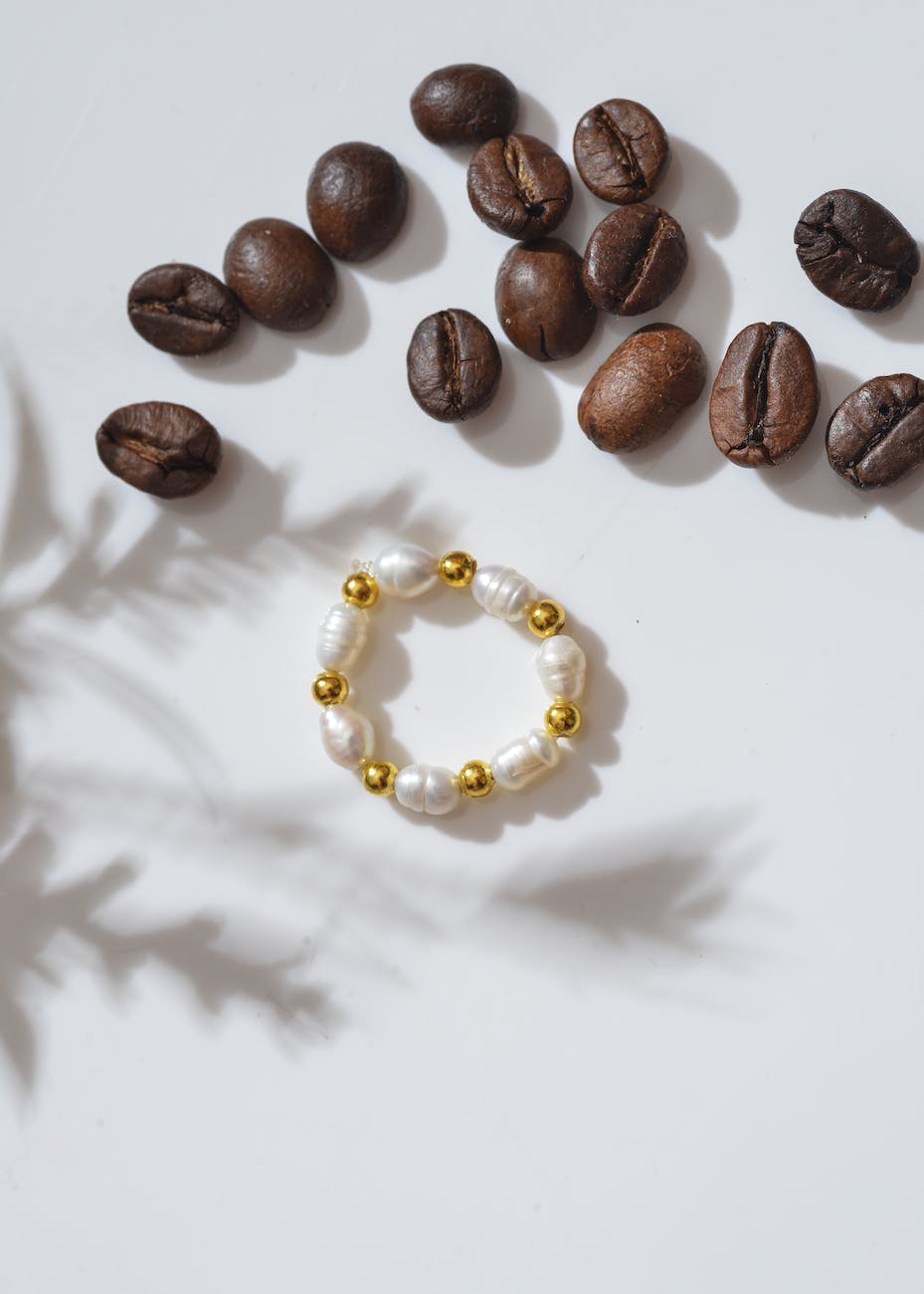 a pearl bracelet beside coffee beans
