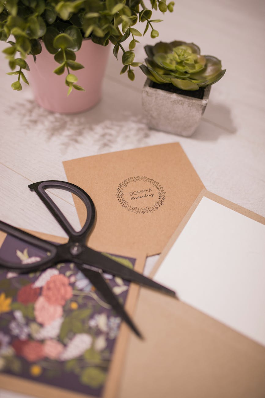 creative invitation cards and scissors placed on table near succulents
