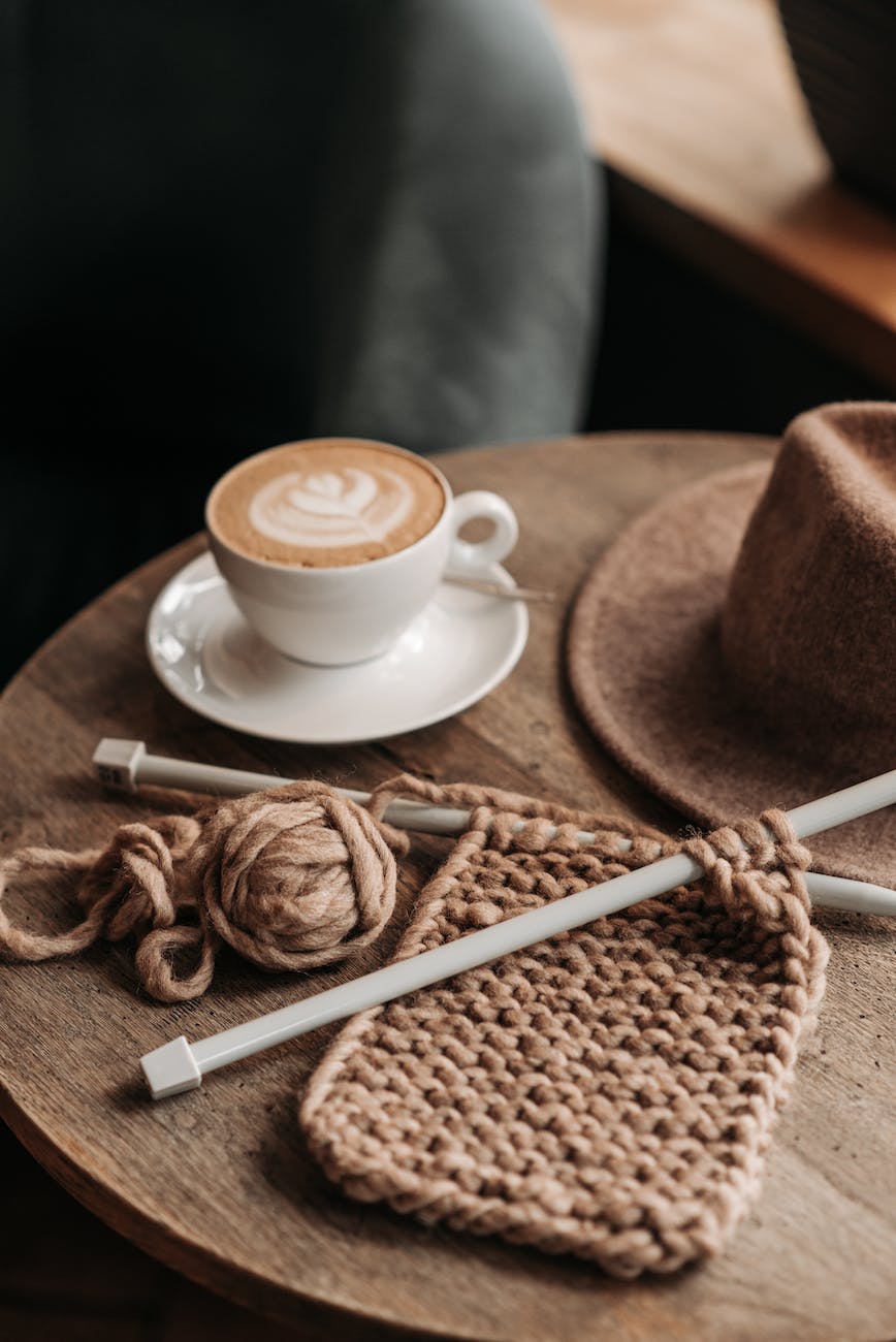 coffee drink beside a knitted material on wooden table