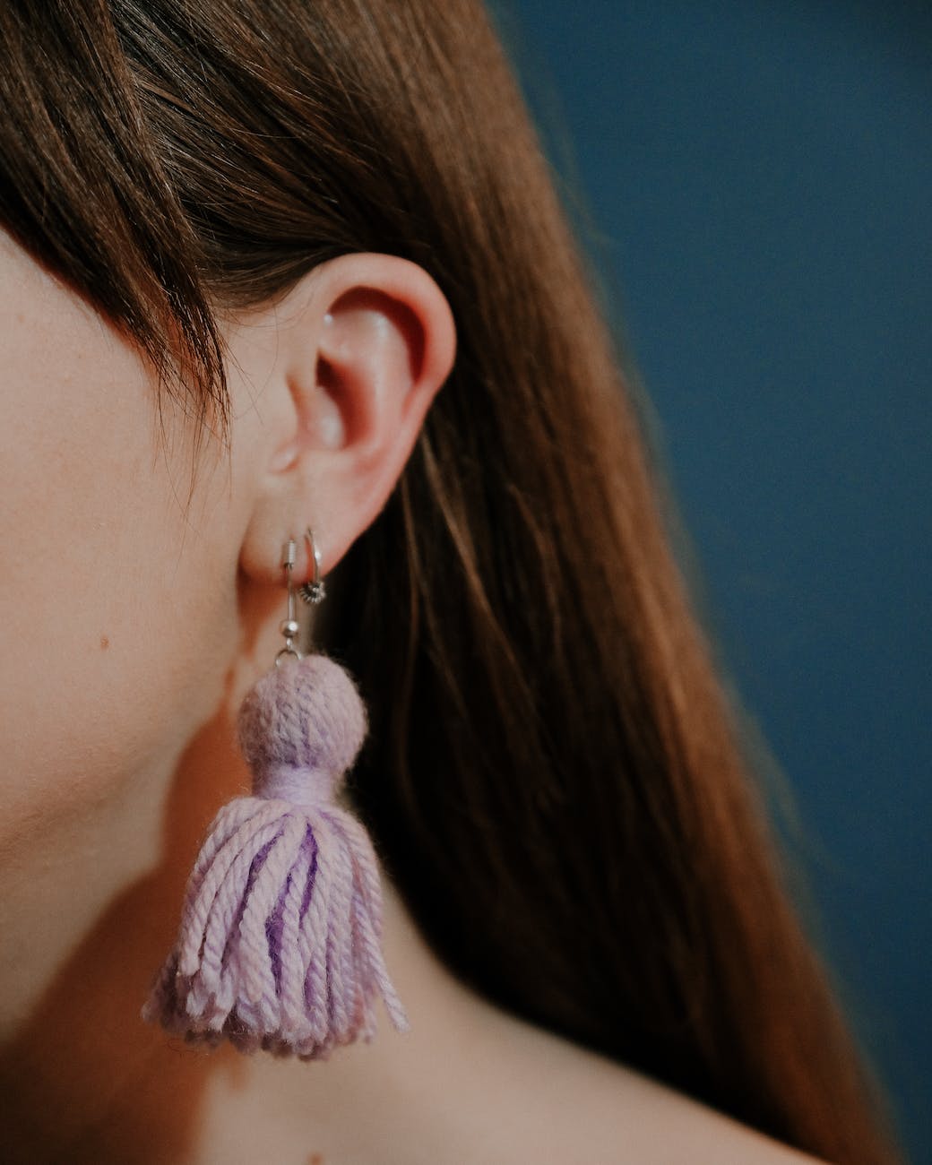 unrecognizable woman wearing earrings with yarn tassels